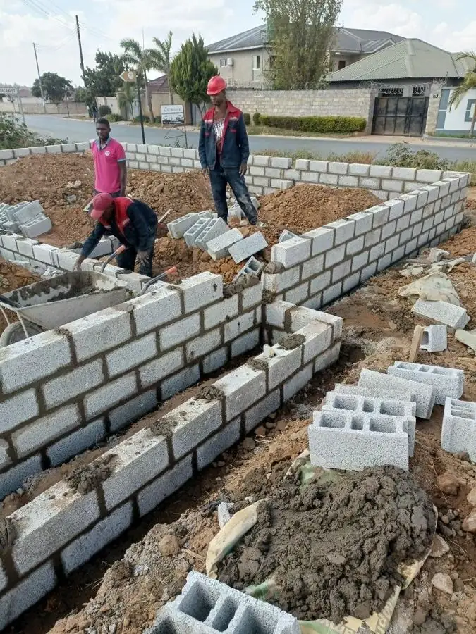 Masons laying sandcrete blocks for foundation walls