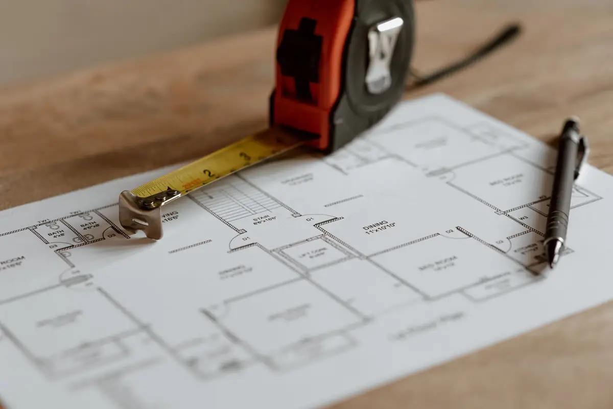 A tape measure and pen on a printed floor plan
